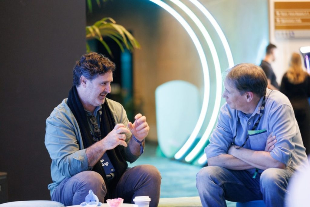 Two delegates deep in conversation beside a neon arch